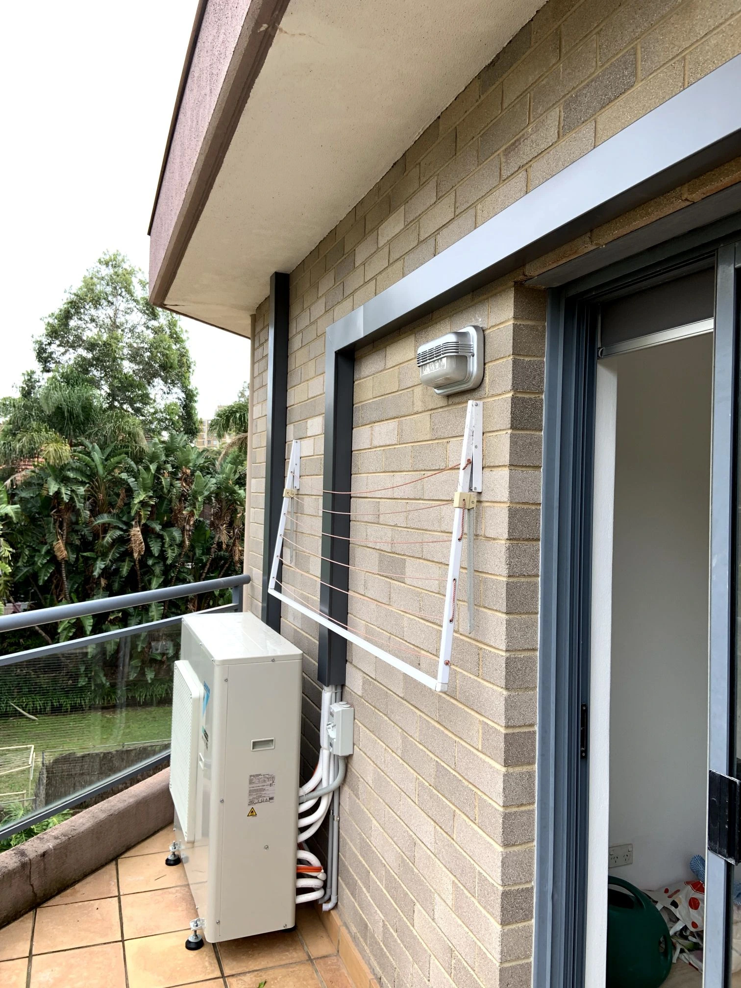 Outdoor condenser and pipework beside a home’s windows