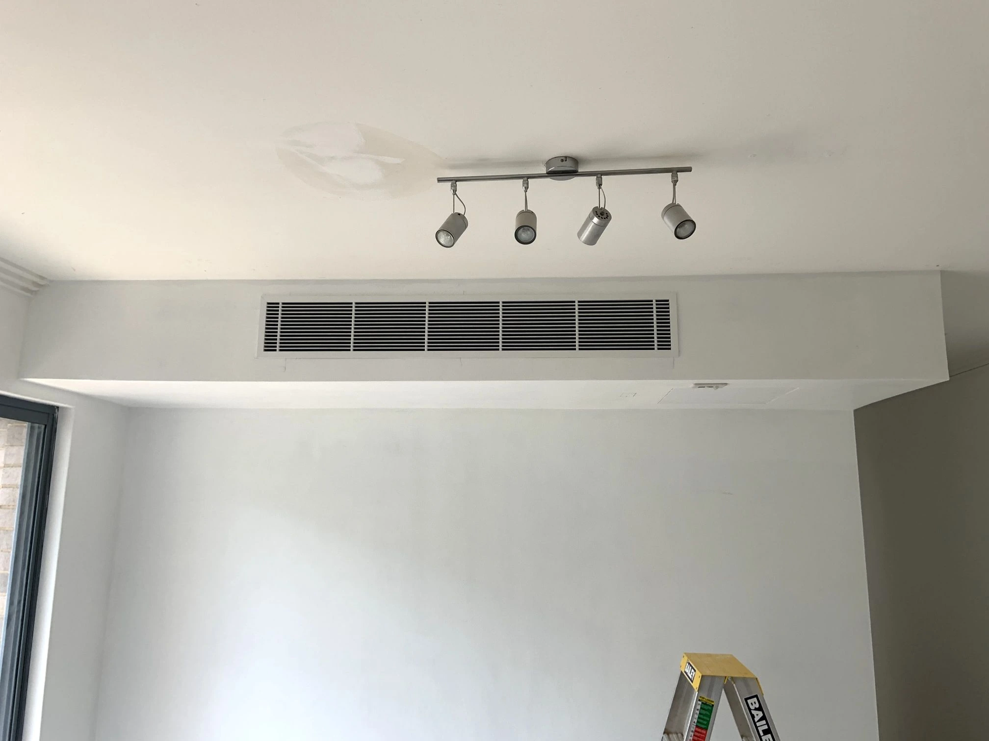 Long ducted air conditioning grille above a living area