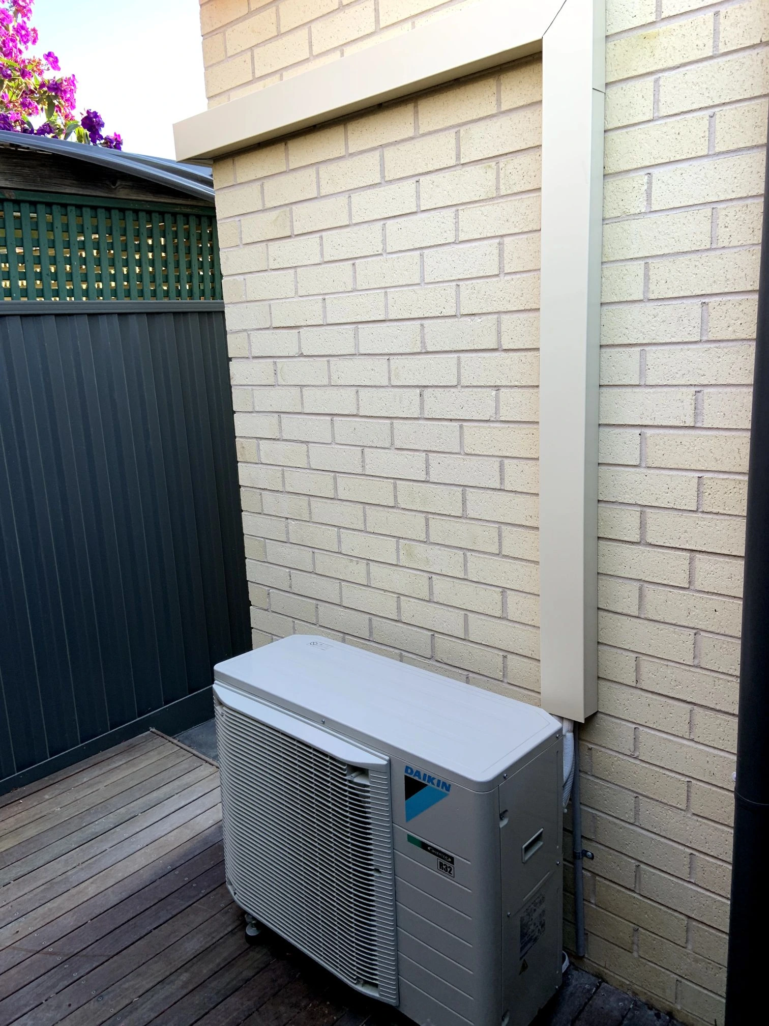 Outdoor condenser installed beside a brick wall and fence